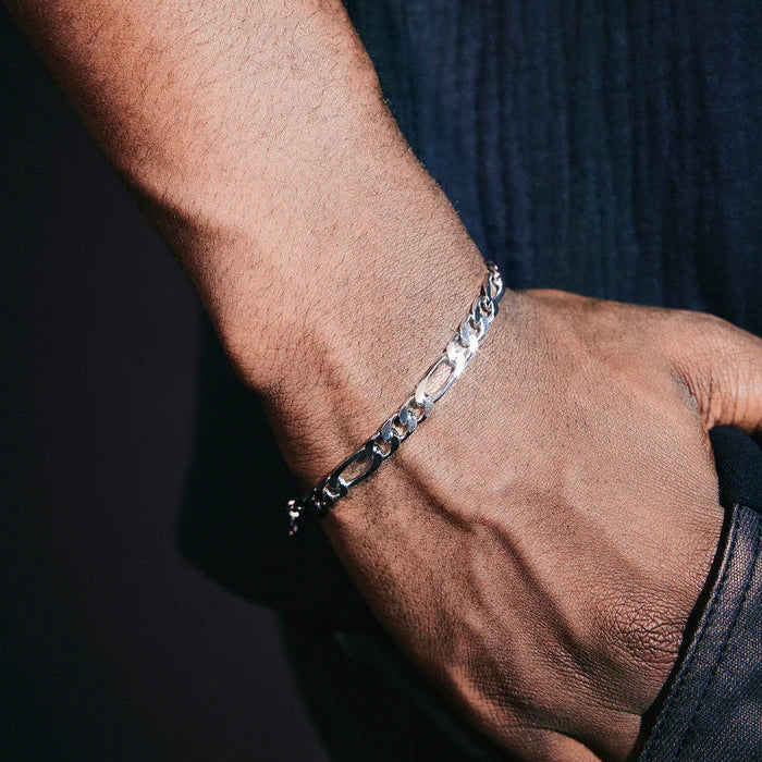 Close-up of a hand wearing a silver bracelet on a dark background