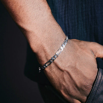 Close-up of a hand wearing a silver bracelet on a dark background