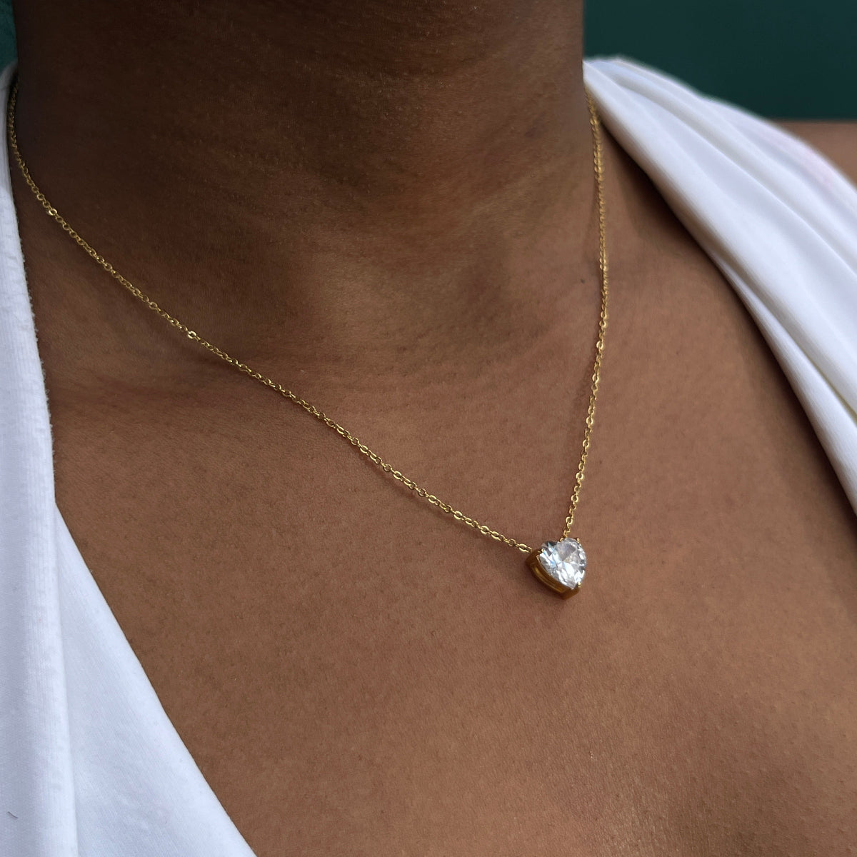 Gold necklace with a diamond pendant on a person's neck