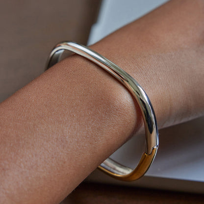 Gold bracelet on a wrist with a neutral background