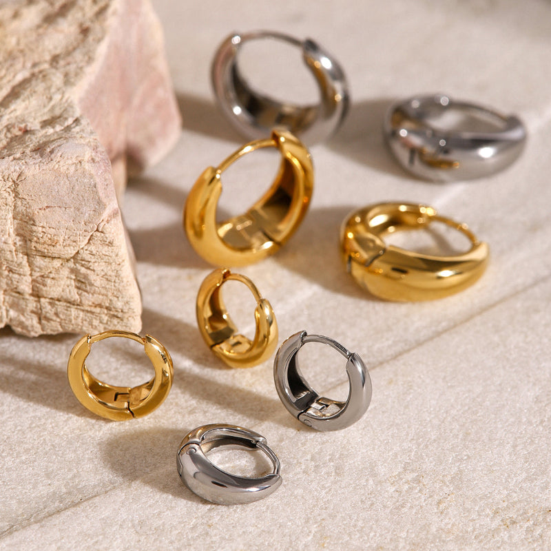 Gold and silver hoop earrings on a textured surface